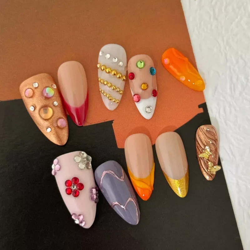 Mixed texture press-on nails with orange flames, floral rhinestones, and chrome swirls