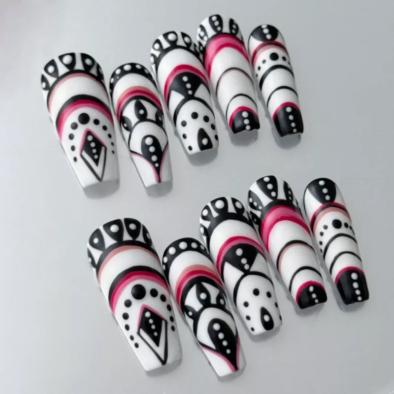 Close-up of red and black patterned press-on nail with tribal and geometric line art