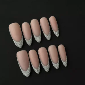 Side view of almond-shaped nude press-on nails with matte finish and silver glitter tips