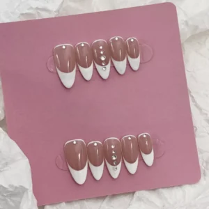 Artistic shot of White French Press-On Nails with nude background and rhinestone charm