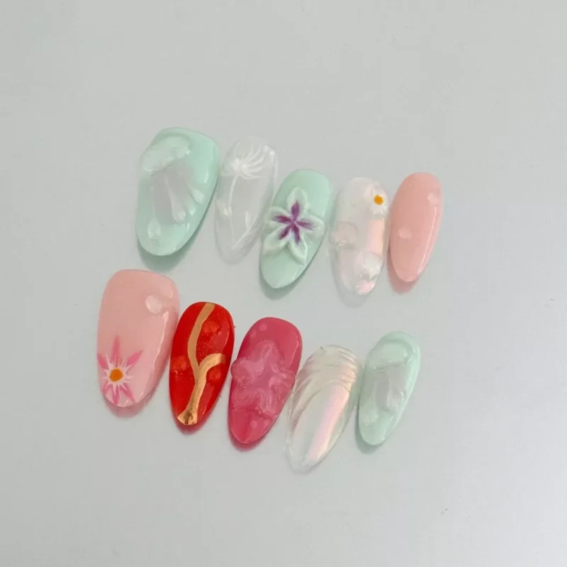 Artistic flower press-on nails featuring colorful 3D designs and pastel shades