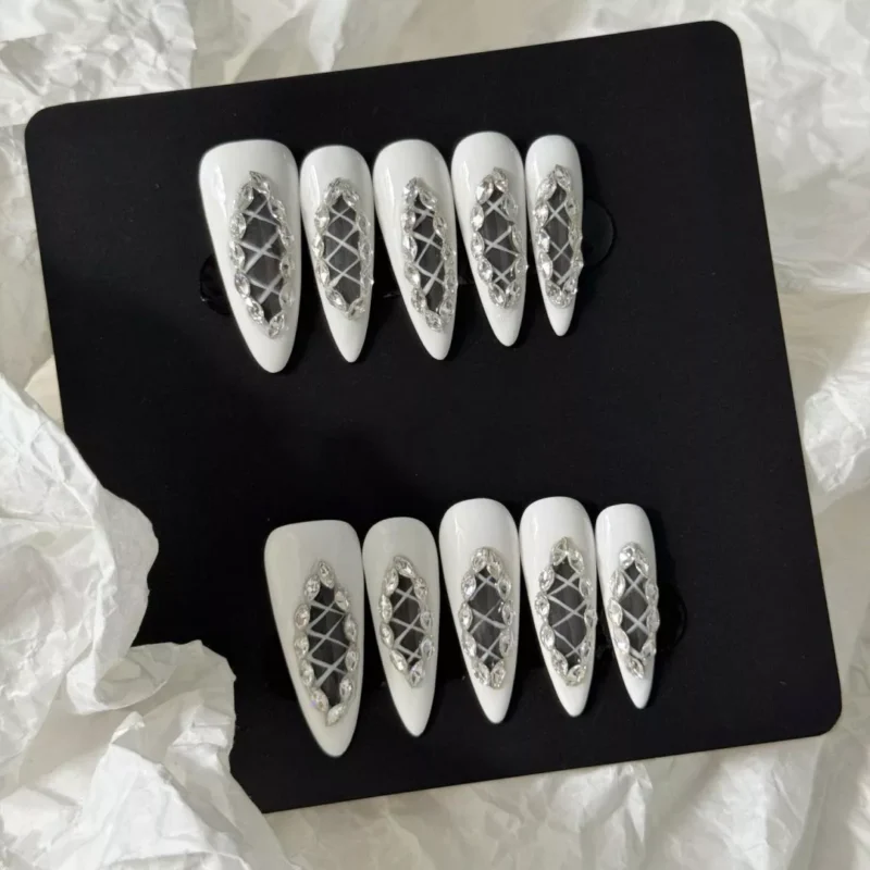 Artistic shot of White Lattice Press-On Nails with rhinestone and cutout details