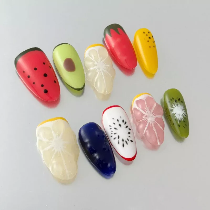Close-up of 3D press-on nail with pink base and avocado fruit accent