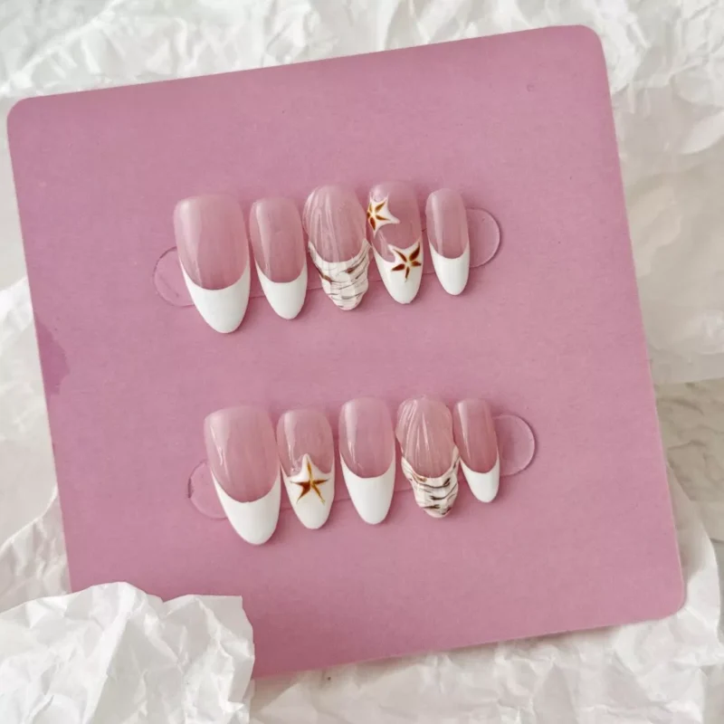 Styled layout of press-on nails with shell and starfish accents in nude and white tones