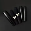 Black press-on nails with matte and glossy finish, glitter bow accents – front display