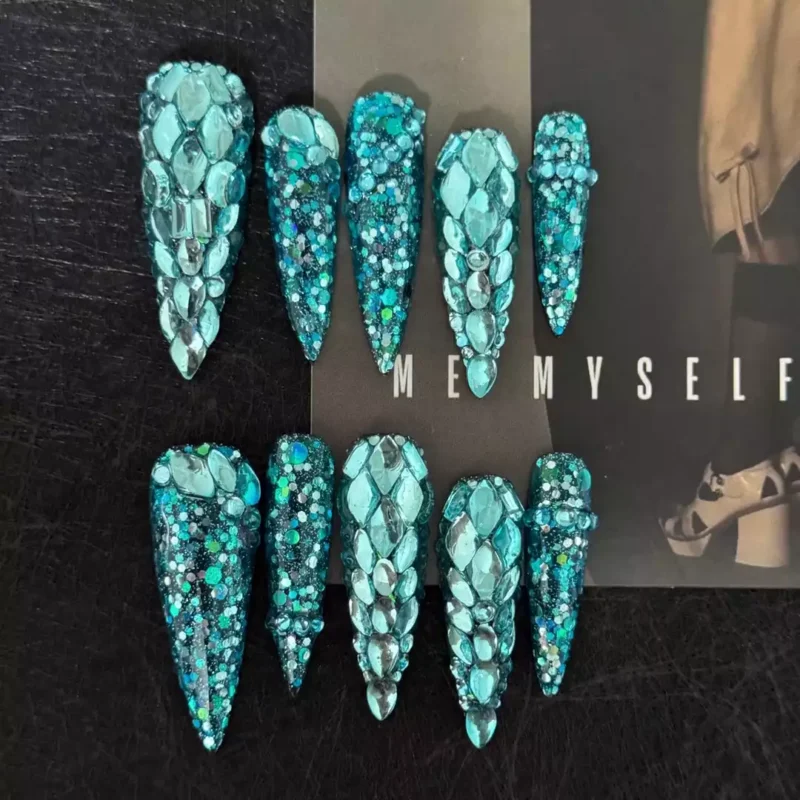 Statement press-on nails in teal glitter with large rhinestones for photoshoots