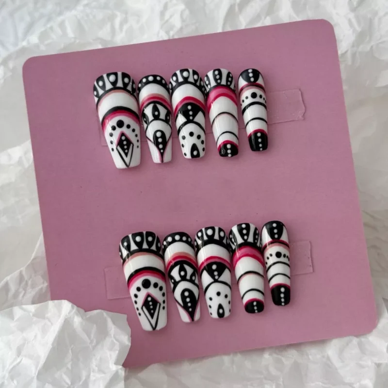 Styled layout of tribal geometric press-on nails with black, white, and red abstract motifs