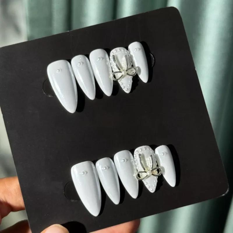 Full set of Pearl White Press-On Nails with beaded 3D bow accents under sunlight