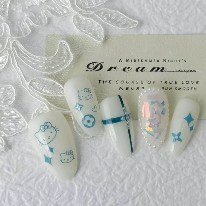 White press-on nails with cartoon and holographic pearl accents on fabric background