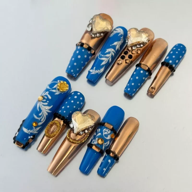 Close-up of Royal Blue Press-On Nails featuring gold highlights and heart crystal charm