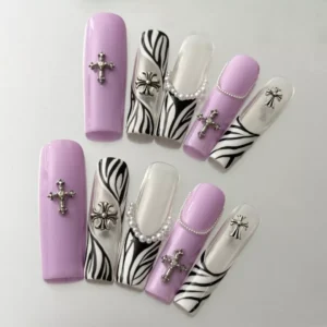 Close-up of cross charm and beaded accent on zebra pattern purple press-on nail