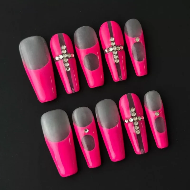 Close-up of matte cross nails with silver crystals on hot pink stiletto base