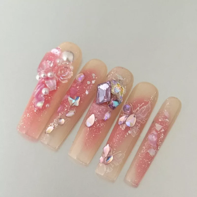 Alt Text: Square nude pink press-on nails with romantic pearl and butterfly design