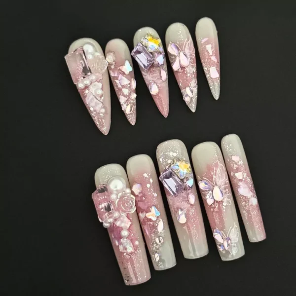 Crystal Blossom Press-On Nails with pink gradient base, pearl and crystal charms, and butterfly details on long stiletto and square tips