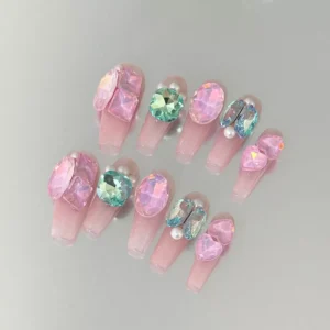 Close-up of blush pink nails with gemstone and pearl cluster accents