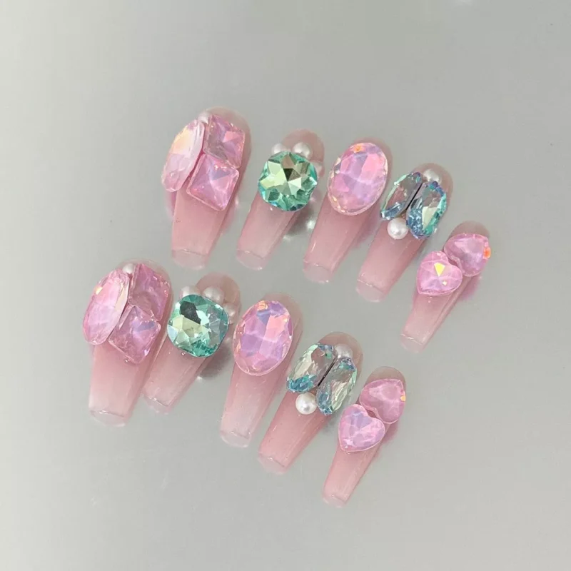 Close-up of blush pink nails with gemstone and pearl cluster accents