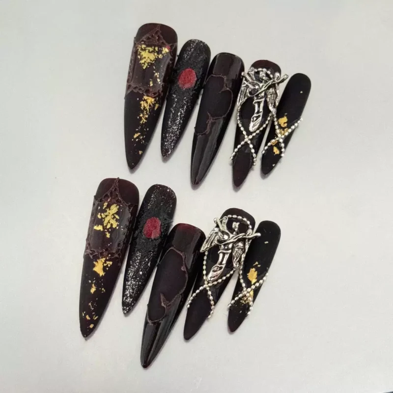 Close-up of red and black stiletto press-on nails with cat eye and textured chrome