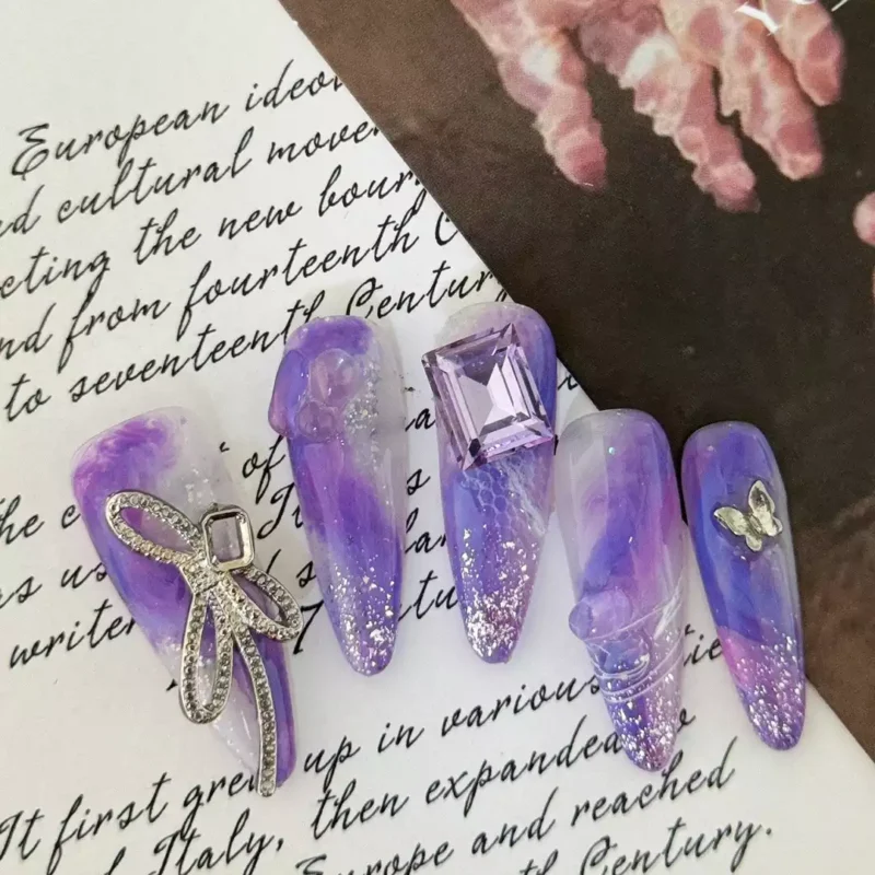 Close-up of 3D crystal bow on purple gradient nail