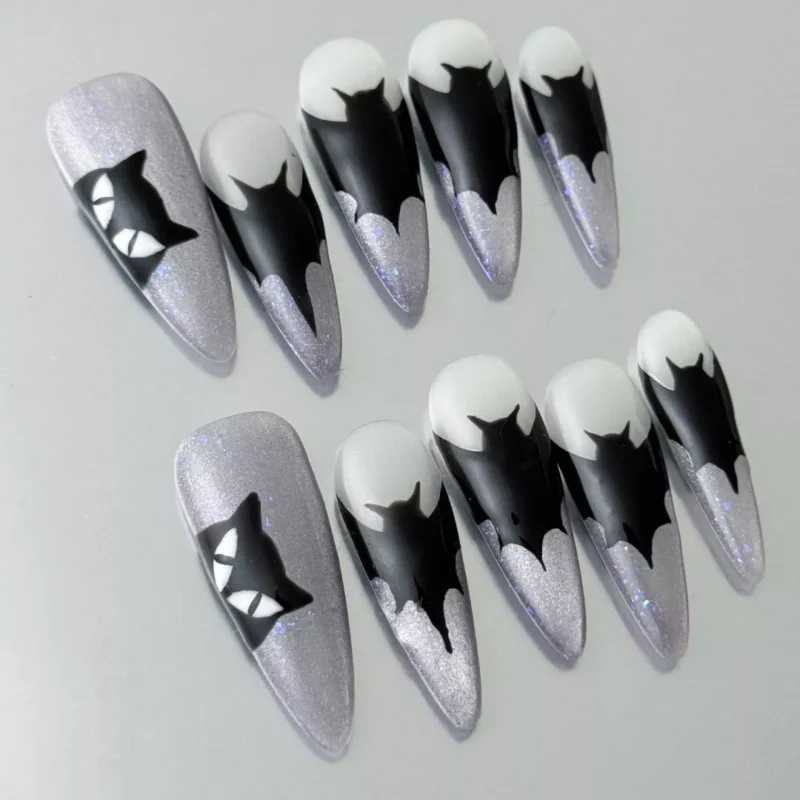 Close-up of black dripping tip on silver glitter stiletto press-on nail with gothic style