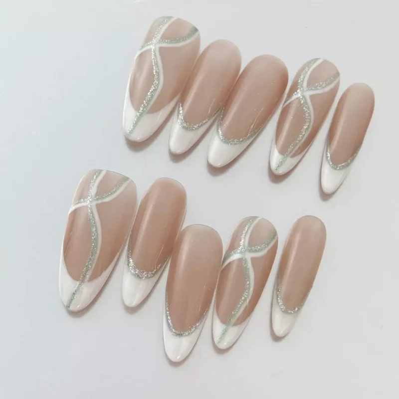 Nude base press-on nails in almond shape with silver glitter accents and clean crossover lines