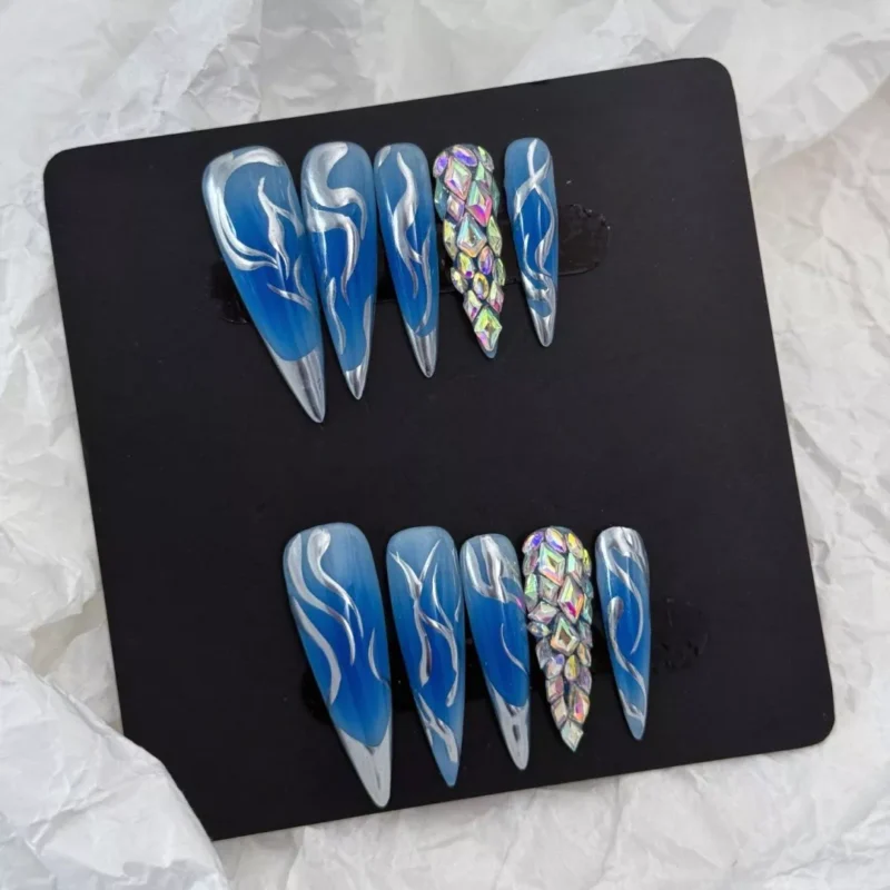 Precision-crafted flames in metallic silver contrast the icy blue background, while faceted rhinestones offer dimensional brilliance and texture.