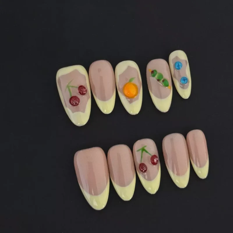 Fruit French Tip Press-On Nails with nude base and yellow tips on black background
