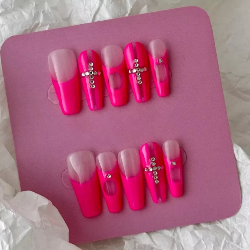Full layout of Y2K pink press-on nails with bold cross details and rhinestones