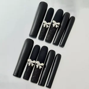 Close-up of glitter bow accent on long black matte press-on nail with square shape