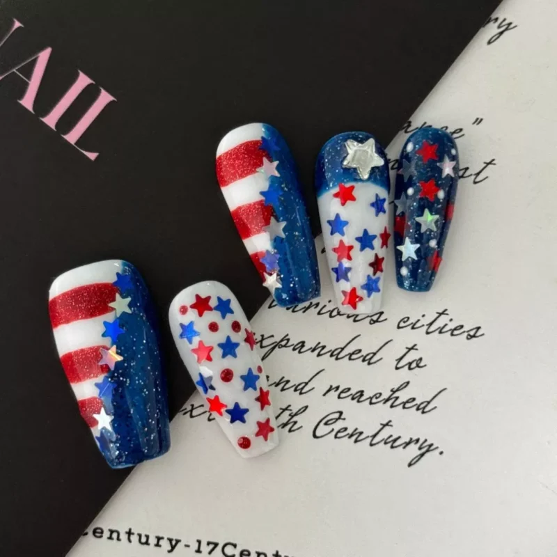 Close-up of glitter star details on red, white, and blue festival nails