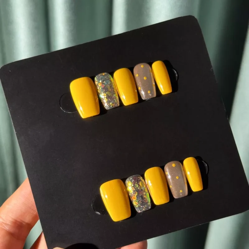 Full set of Yellow Glitter Square Press-On Nails with colorful foil and dot accents on display card