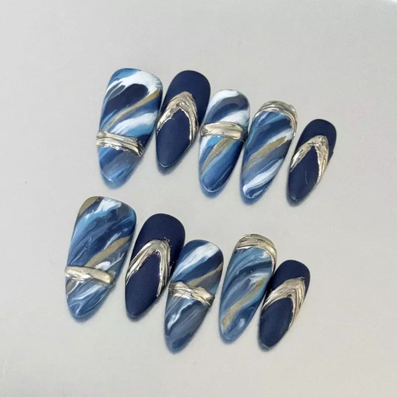 Close-up of Gold Brushstroke Press-On Nails featuring navy marble base