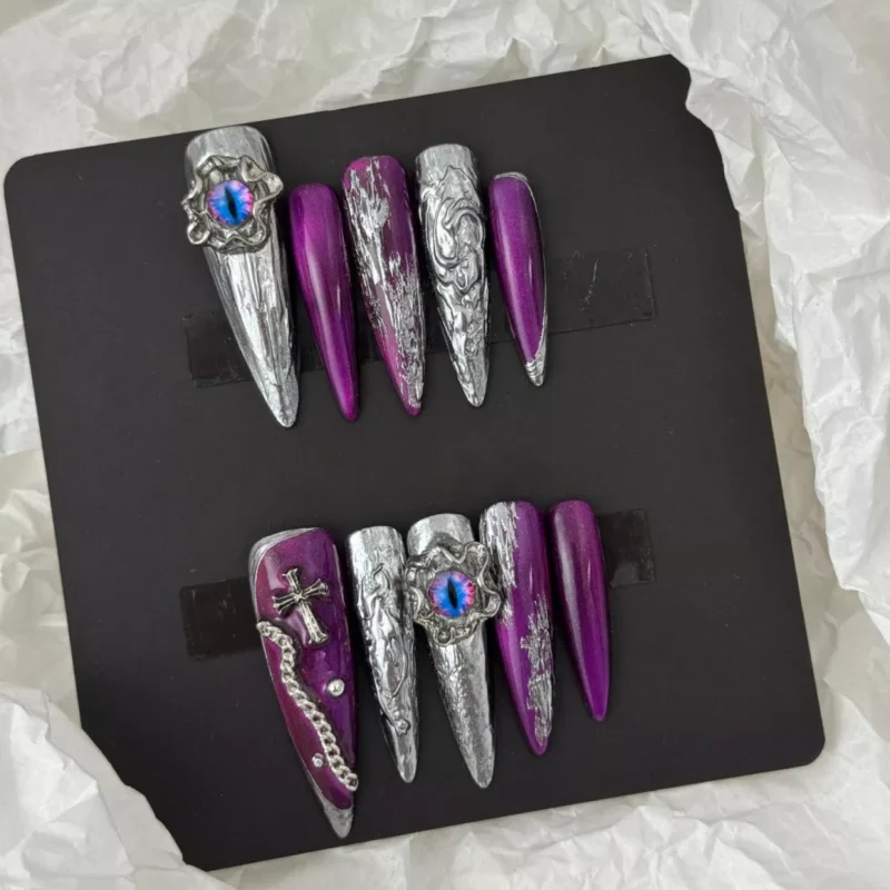 Angled shot of gothic purple press-on nails with silver flame and claw-like shape