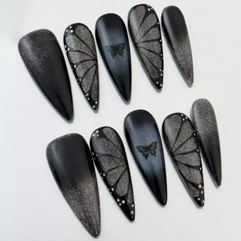 Black gradient stiletto nails with gothic butterfly embellishment – side angle