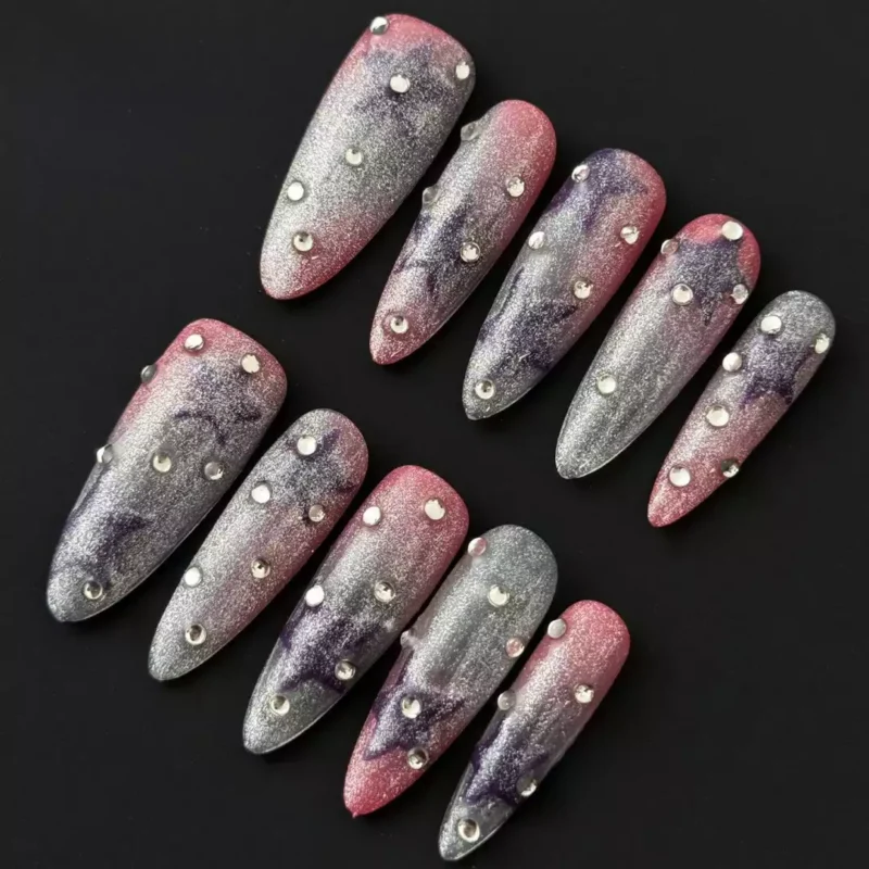 Starry glitter press-on nails with rhinestone accents and pink to purple gradient