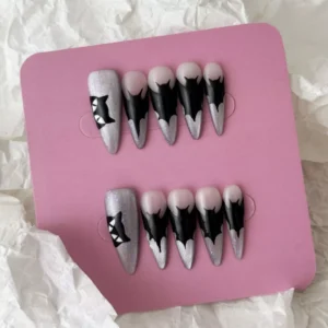 Flat lay of gothic press-on nails with black dripping tips and cat silhouette on glitter base