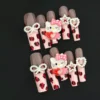 Leopard Kitty Press-On Nails with 3D cartoon charm and pearl heart accents on pink base