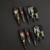 Dark Spell Press-On Nails - Gothic Cat Eye Halloween Design 5 Gothic stiletto press-on nails in deep red and black with cat eye shimmer, cracked texture, and silver angel charms – Dark Spell Press-On Nails design.