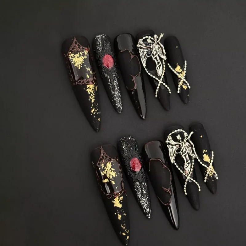 Gothic stiletto press-on nails in deep red and black with cat eye shimmer, cracked texture, and silver angel charms – Dark Spell Press-On Nails design.