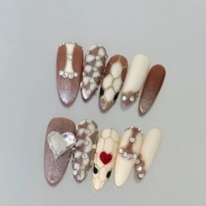 Stiletto shape press-on nails in nude and brown with geometric scales and diamond heart detail
