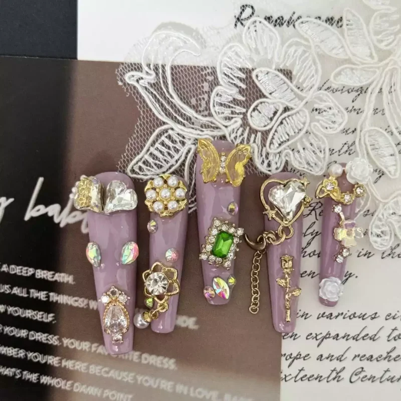 Flat lay of Baroque Press-On Nails on lace and paper backdrop with royal detailing