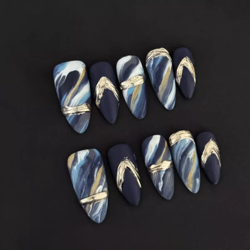 Matte Blue Marble Press-On Nails with gold brushstroke accents on black background