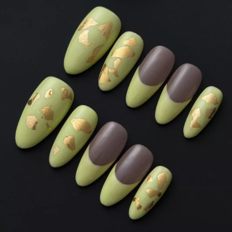Matte light green press-on nails with taupe French tips and gold foil – flat lay view
