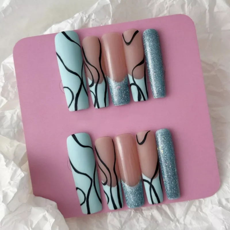 Hand model wearing mint nude press-on nails with black abstract waves and shimmer edges