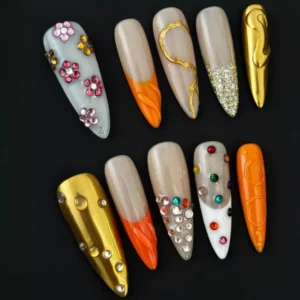 Side angle of mixed orange nails showing texture and layered embellishment