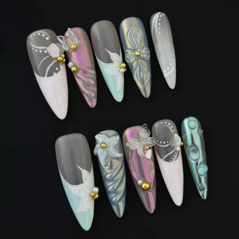 Mixed pastel press-on nails featuring 3D flower and butterfly accents with gold bead details – top view