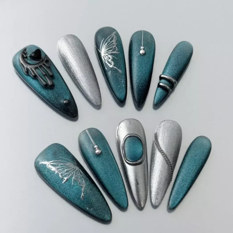 Close-up of gothic moon charm and silver chain on teal glitter press-on nail