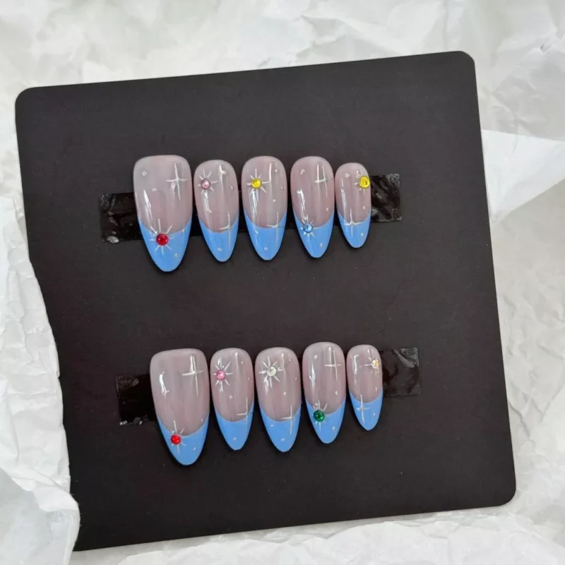 Multicolor gem nail art with silver stars on sheer nude base – close-up detail