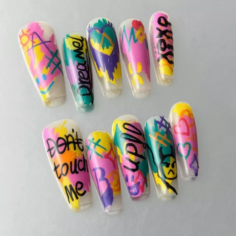 Close-up of hand-drawn letter nail art with colorful neon street tag graphics