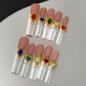 Nude and white press-on nails with gold-framed crystal gems