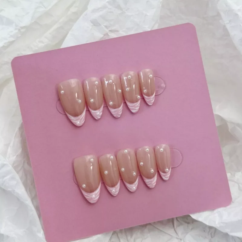 Pearl Pink Press-On Nails pastel swirl tips and pearls - close-up on fingers